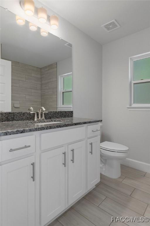 bathroom with visible vents, baseboards, toilet, and vanity