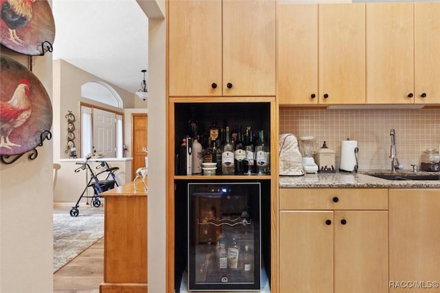 bar with sink, beverage cooler, light brown cabinetry, and decorative backsplash