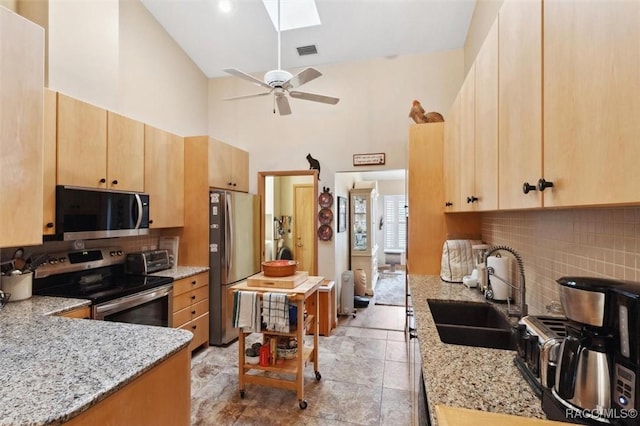 kitchen with sink, stainless steel appliances, light stone counters, tasteful backsplash, and light brown cabinetry