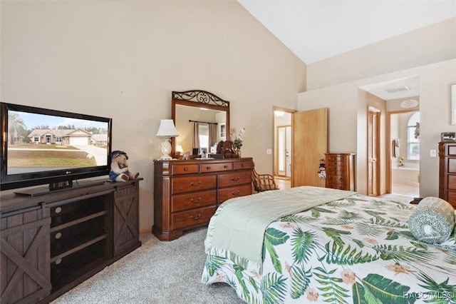 bedroom featuring ensuite bathroom, light colored carpet, and high vaulted ceiling