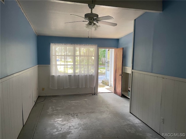 120 NW Magnolia Cir, Crystal River, FL 34428 - unfurnished room with wainscoting, unfinished concrete floors, ceiling fan, and wood walls
