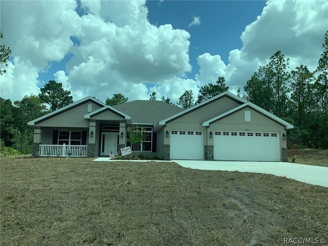 view of front facade featuring covered porch, a garage, and a front yard