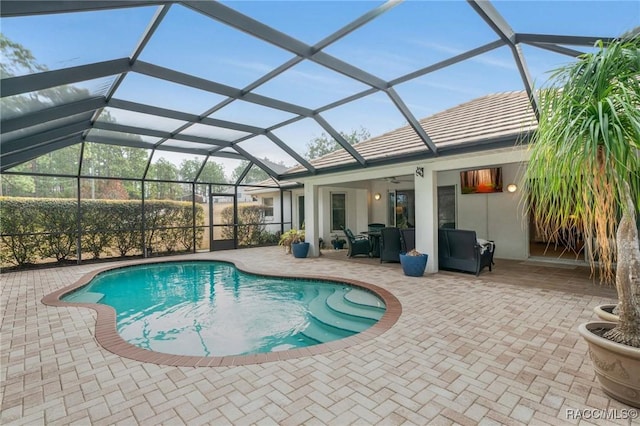 view of pool with a patio, ceiling fan, and glass enclosure