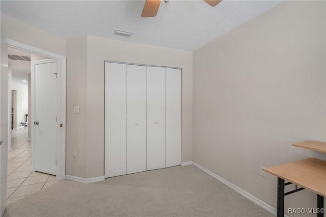 unfurnished bedroom with light carpet, a closet, and ceiling fan