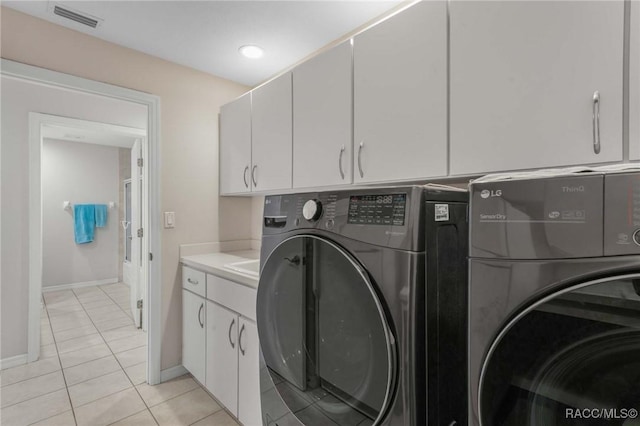 laundry room with light tile patterned floors, washing machine and dryer, and cabinets