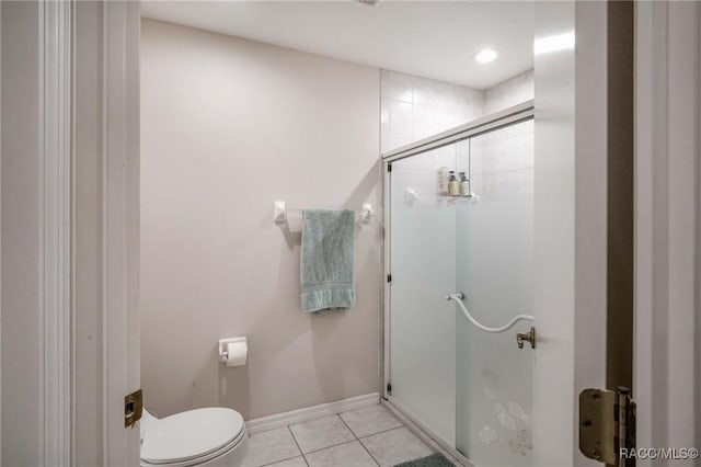 bathroom featuring tile patterned flooring, a shower with door, and toilet