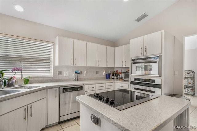 kitchen featuring lofted ceiling, a center island, tasteful backsplash, black electric stovetop, and stainless steel dishwasher