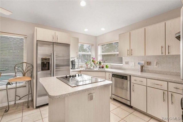 kitchen with backsplash, stainless steel appliances, a kitchen island, and light tile patterned floors