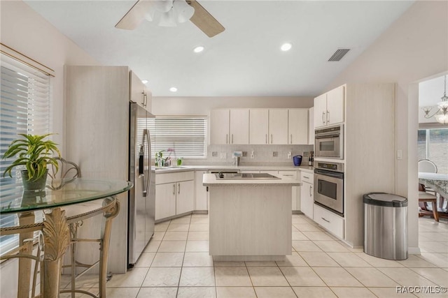 kitchen with light tile patterned flooring, sink, a center island, stainless steel appliances, and decorative backsplash