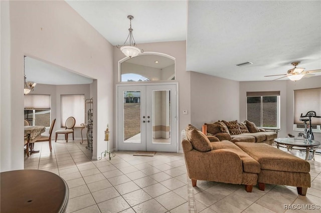 living room featuring ceiling fan with notable chandelier, french doors, and light tile patterned flooring