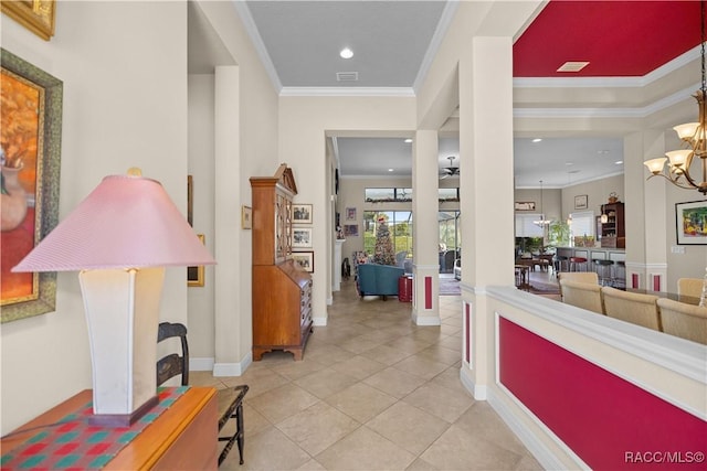 hall with decorative columns, crown molding, light tile patterned floors, and a chandelier