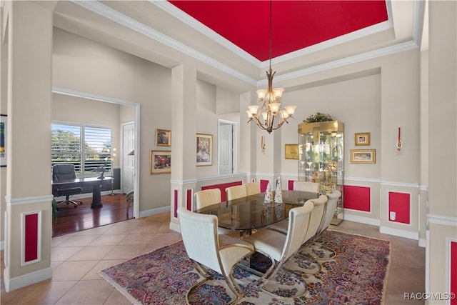 tiled dining area featuring a high ceiling, a tray ceiling, crown molding, and a notable chandelier