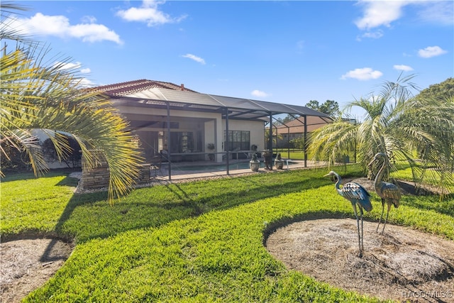 rear view of house with a pool, glass enclosure, a patio area, and a lawn