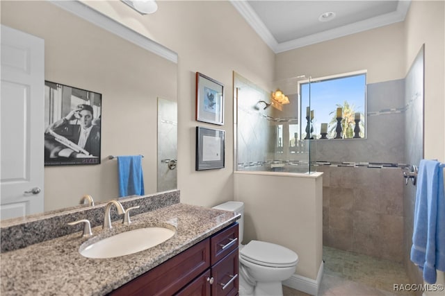 bathroom featuring tiled shower, toilet, vanity, and ornamental molding