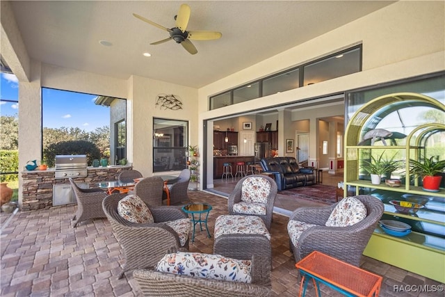 view of patio featuring exterior kitchen, ceiling fan, an outdoor living space, a grill, and exterior bar