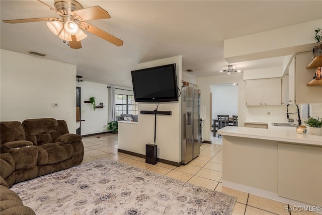 living room featuring ceiling fan, sink, and light tile patterned flooring