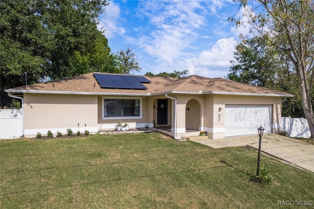 single story home with solar panels, a garage, and a front lawn