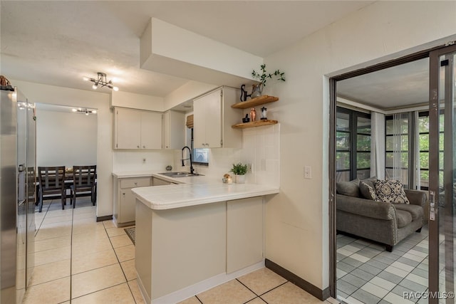 kitchen featuring decorative backsplash, kitchen peninsula, sink, and light tile patterned floors