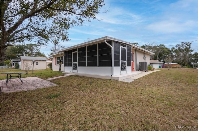 rear view of house with cooling unit, a patio, a sunroom, and a lawn