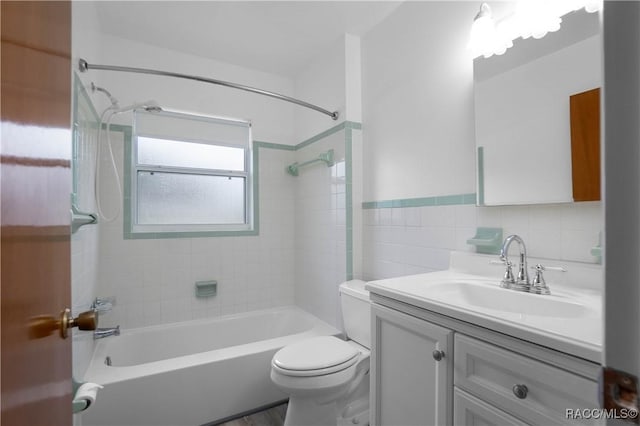 full bathroom featuring vanity, tiled shower / bath, tile walls, and toilet