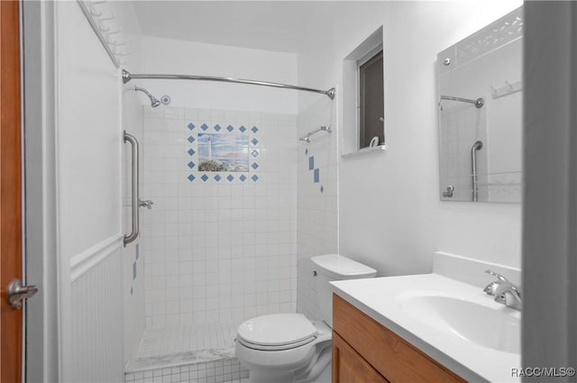 bathroom featuring vanity, a tile shower, and toilet