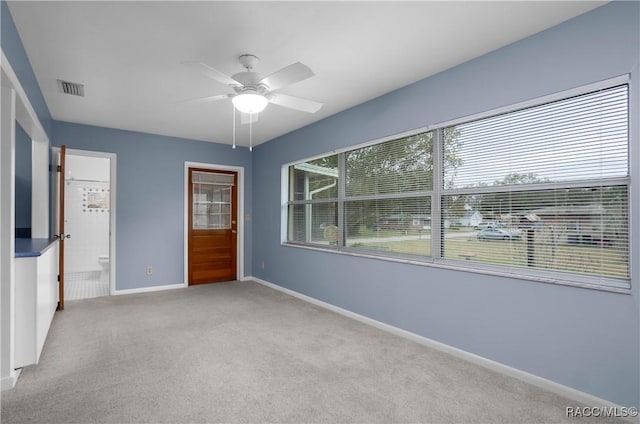 unfurnished bedroom featuring ensuite bathroom, light colored carpet, and ceiling fan