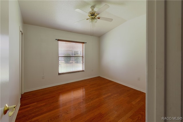 empty room featuring hardwood / wood-style flooring, vaulted ceiling, and ceiling fan