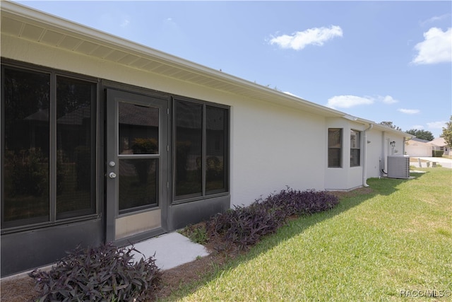 view of side of home with a yard and central AC