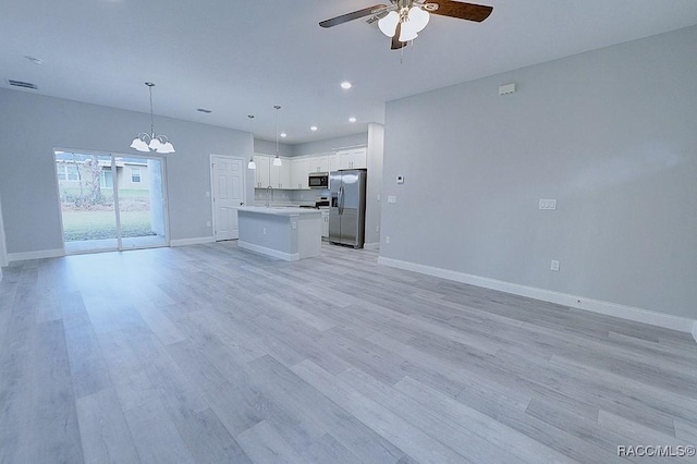 unfurnished living room with ceiling fan with notable chandelier, light hardwood / wood-style flooring, and sink