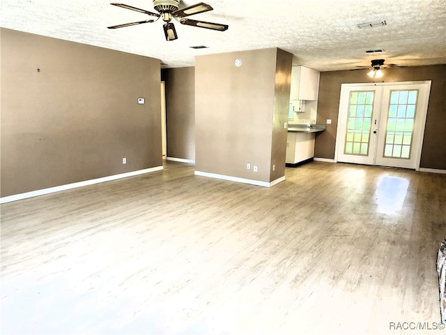 unfurnished living room featuring ceiling fan, light hardwood / wood-style floors, a textured ceiling, and french doors