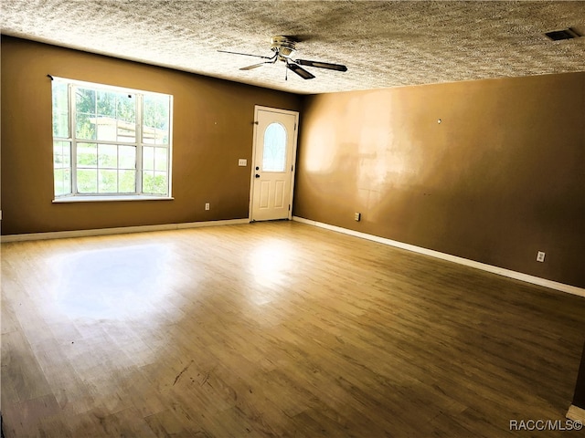 empty room featuring ceiling fan, wood-type flooring, and a textured ceiling