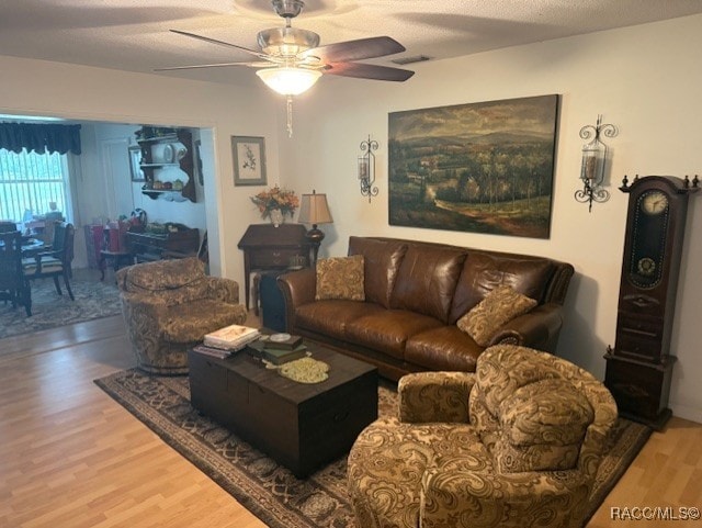 living area with visible vents, ceiling fan, and wood finished floors