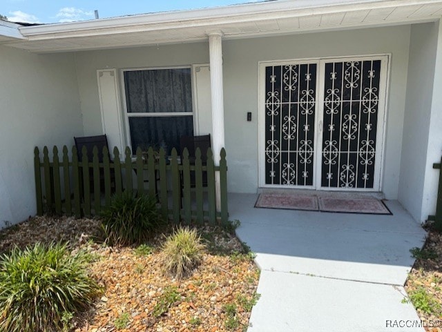entrance to property with stucco siding and covered porch