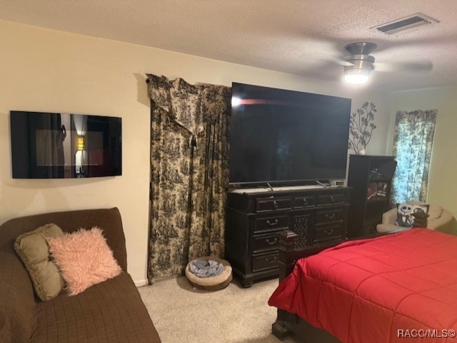 carpeted bedroom featuring a textured ceiling, visible vents, and ceiling fan