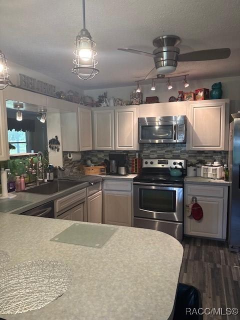 kitchen featuring ceiling fan, light countertops, dark wood finished floors, stainless steel appliances, and decorative backsplash