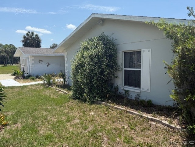 view of side of home with a lawn and stucco siding