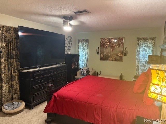 bedroom featuring visible vents, a textured ceiling, carpet, and a ceiling fan