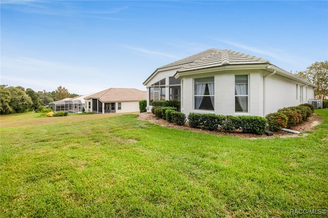 back of property with a tile roof, a lawn, and stucco siding