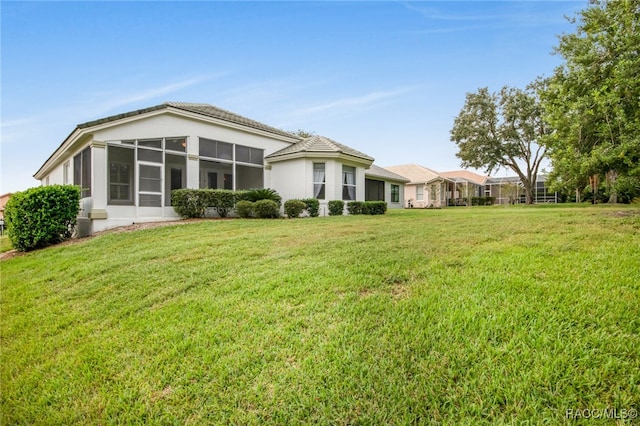 back of house featuring a yard and a sunroom