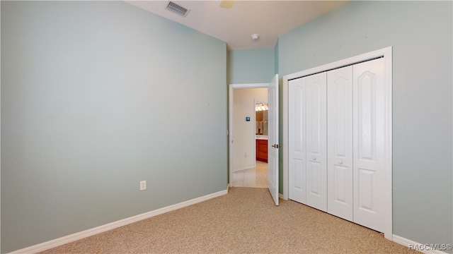 unfurnished bedroom featuring visible vents, baseboards, light colored carpet, and a closet