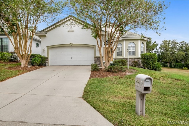 view of front of property with driveway, stucco siding, a front lawn, stone siding, and a garage