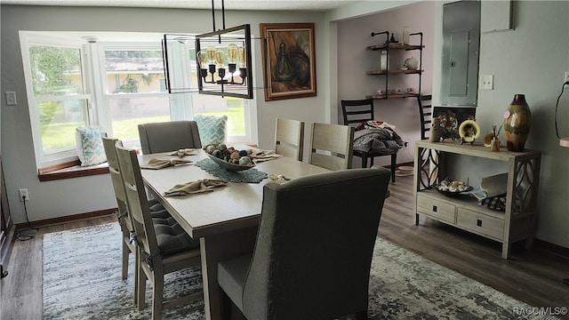 dining space featuring dark wood-type flooring, electric panel, and a chandelier