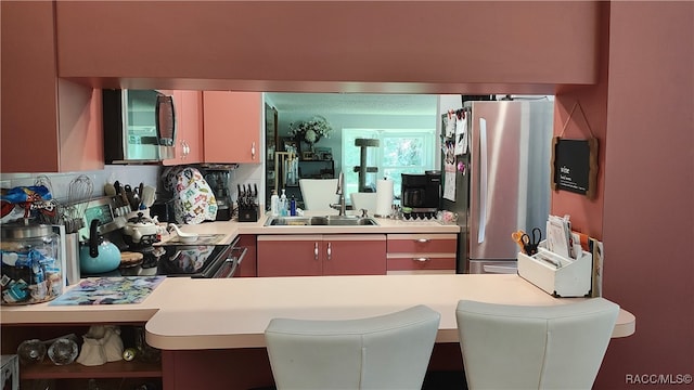 kitchen with kitchen peninsula, sink, a kitchen bar, and stainless steel appliances