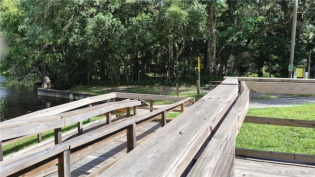 wooden deck with a water view and a lawn