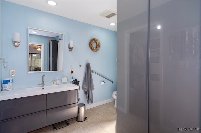 bathroom with a shower, vanity, tile patterned flooring, and toilet