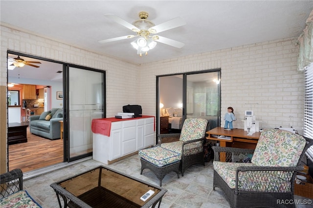 living room with ceiling fan and brick wall