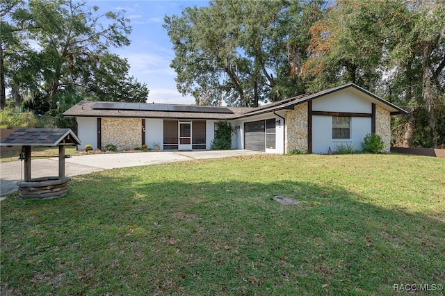 single story home with solar panels, a garage, and a front lawn