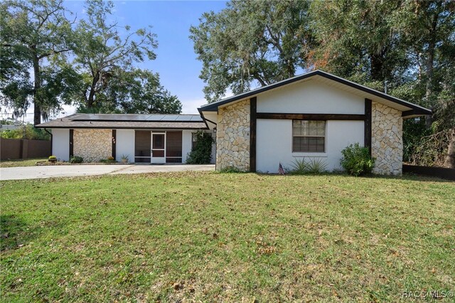 view of front of property with a front yard and solar panels