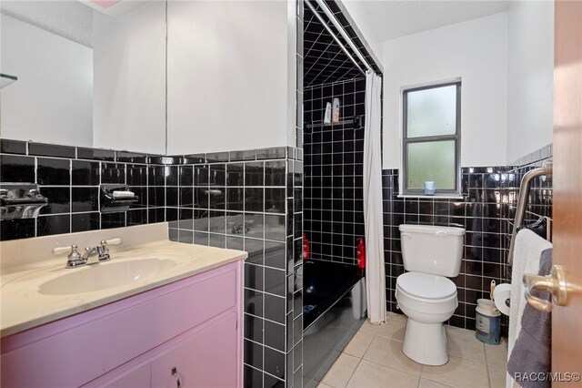 bathroom with a textured ceiling, vanity, tile walls, tile patterned flooring, and toilet