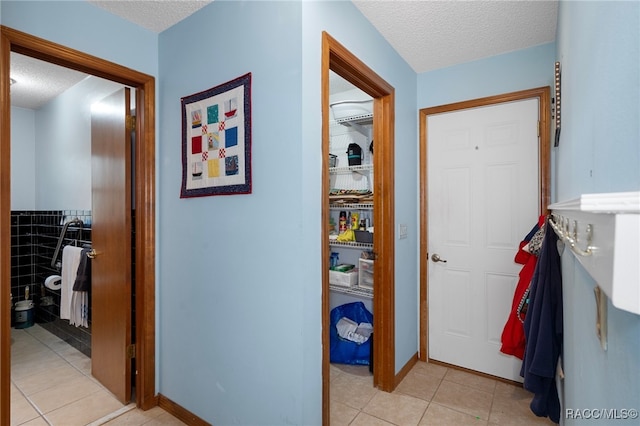 hallway with light tile patterned flooring and a textured ceiling